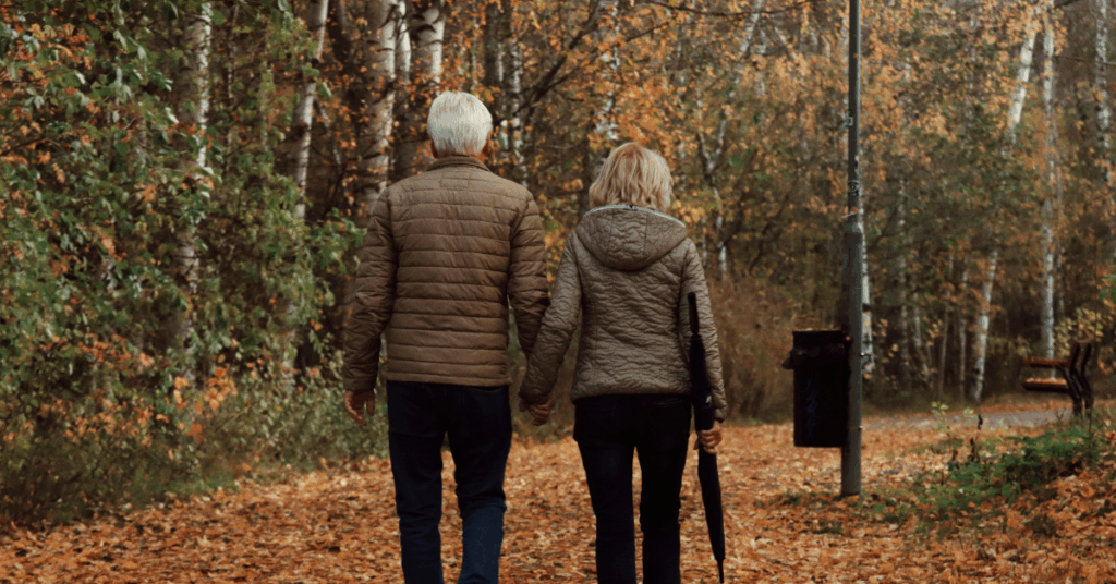 Older couple walking together in a fall forest, reflecting a calm approach to preparing for retirement with confidence.