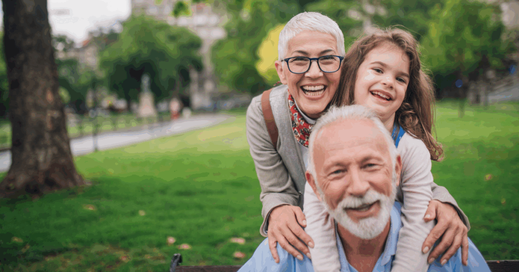 Grandparents smiling with their granddaughter at a park, symbolizing the confidence and freedom that come from purpose-first financial planning for business owners.
