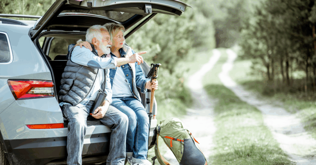 Older couple sitting at the back of their car on a hiking trail, reflecting on retirement and estate planning decisions