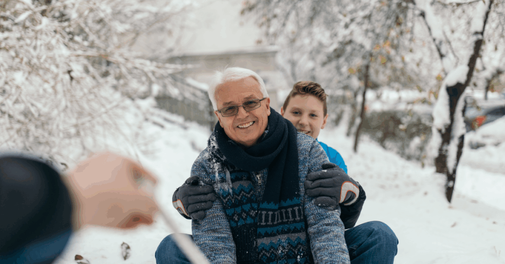 Grandfather and grandson sitting together on a sled in winter, sharing a quiet holiday moment that reflects financial clarity during the holidays and being present with family.