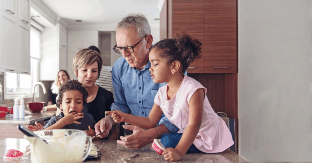 Grandparents baking with their grandchildren at home, representing family values, legacy, and teaching the next generation.